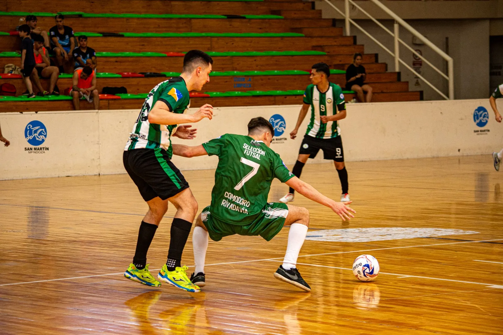 Futsal-ottelu sisähallissa, pelaajat taistelevat pallosta parkettikentällä