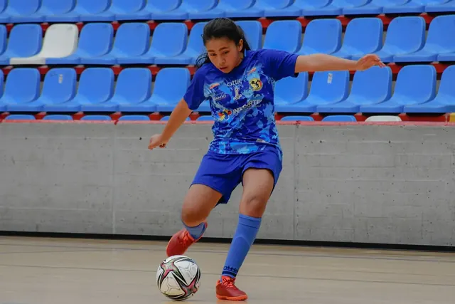 Futsalpelaaja potkaisee palloa sisäkentällä futsalkengät jalassa